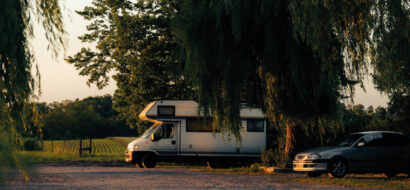 Ein Wohnmobil steht idyllisch unter Bäumen, perfekt für entspanntes Camping in der Natur.