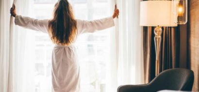 Ein Hotelgast startet den Tag entspannt mit Blick aus dem Fenster und Frühstück im Zimmer.
