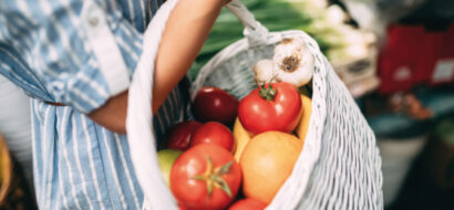 Ein Korb voller frischer Tomaten, Zitrusfrüchte und Knoblauch vom Markt.