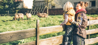 Mutter und Kind bestaunen Schafe auf einem idyllischen Bauernhof.