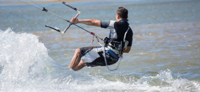 Ein Wassersportler gleitet beim Kitesurfen über die Wellen.