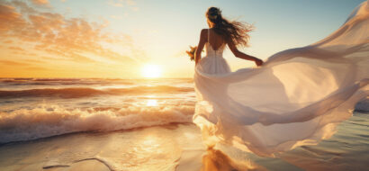 Eine Braut läuft in ihrem Kleid über den Strand und genießt den Sonnenuntergang am Meer.